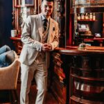 Man standing at bar in Carnaby beige suit
